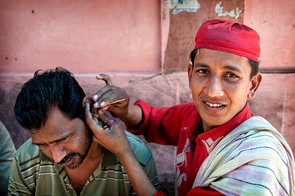 Indie mężczyzna przekłuwa ucho drugiemu mężczyźnie